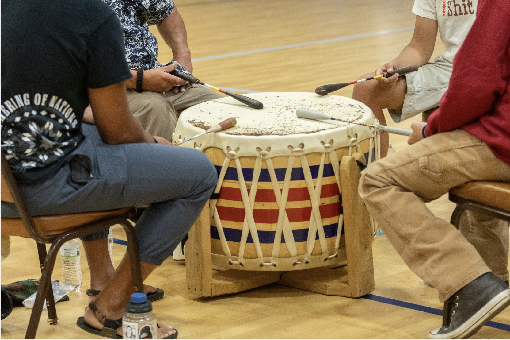Four men gather around a drum to sing traditional Penobscot songs.