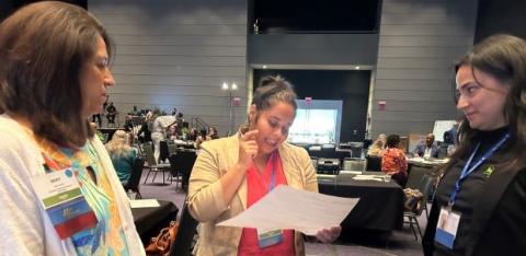 A student presents during the symposium as her teacher and a NeighborWorks staff member listen.