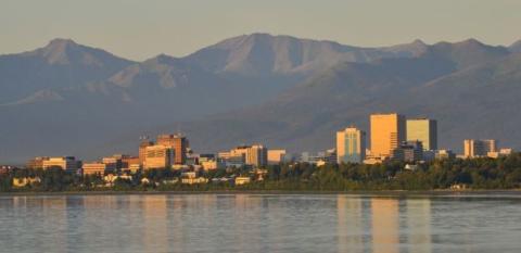 A scene shows the skyline of Anchorage, Alaska, with water and a mountain in the backgrounds.